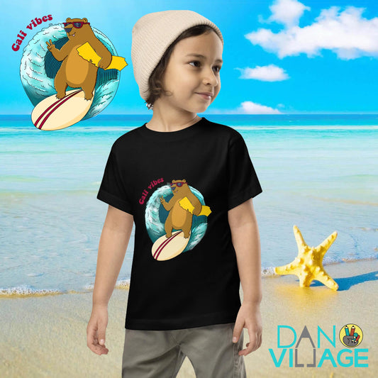 Illustrated surf tee for toddlers featuring a bear on a surfboard throwing a shaka